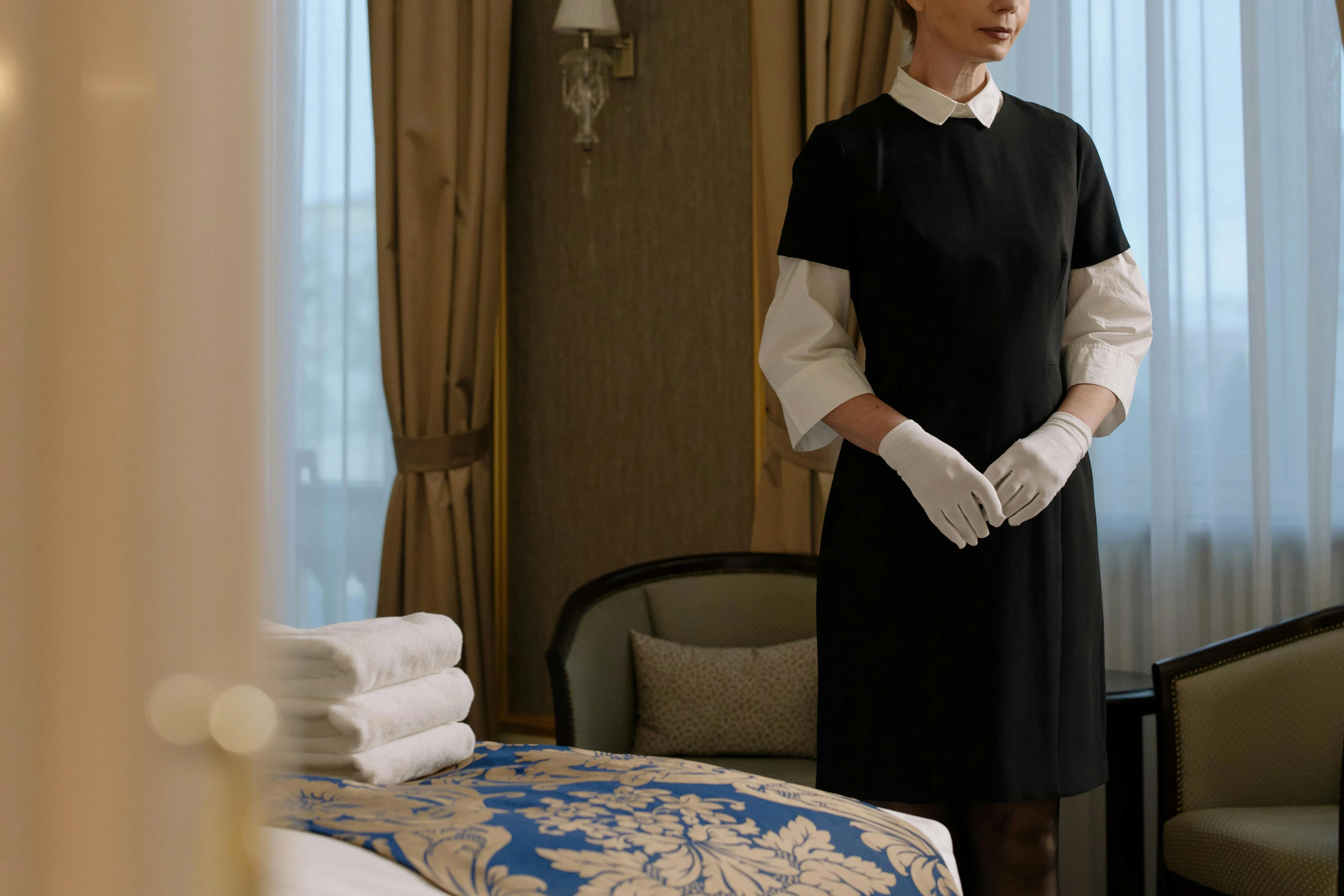 A maid/nanny wearing maid uniform in Dubai and standing along the bed side 