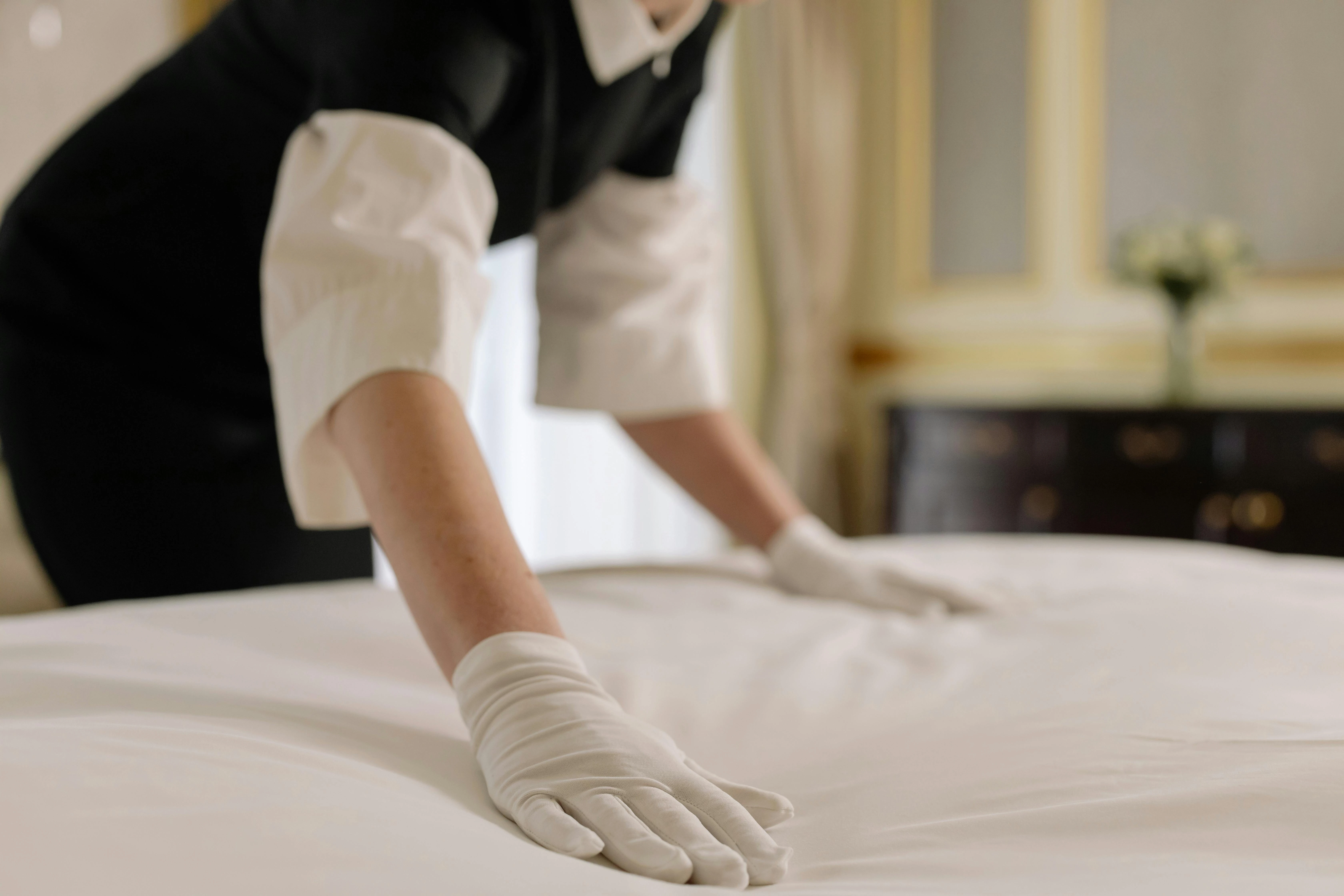 a nanny in duabi is setting the blanket of the bed wearing her maid uniform