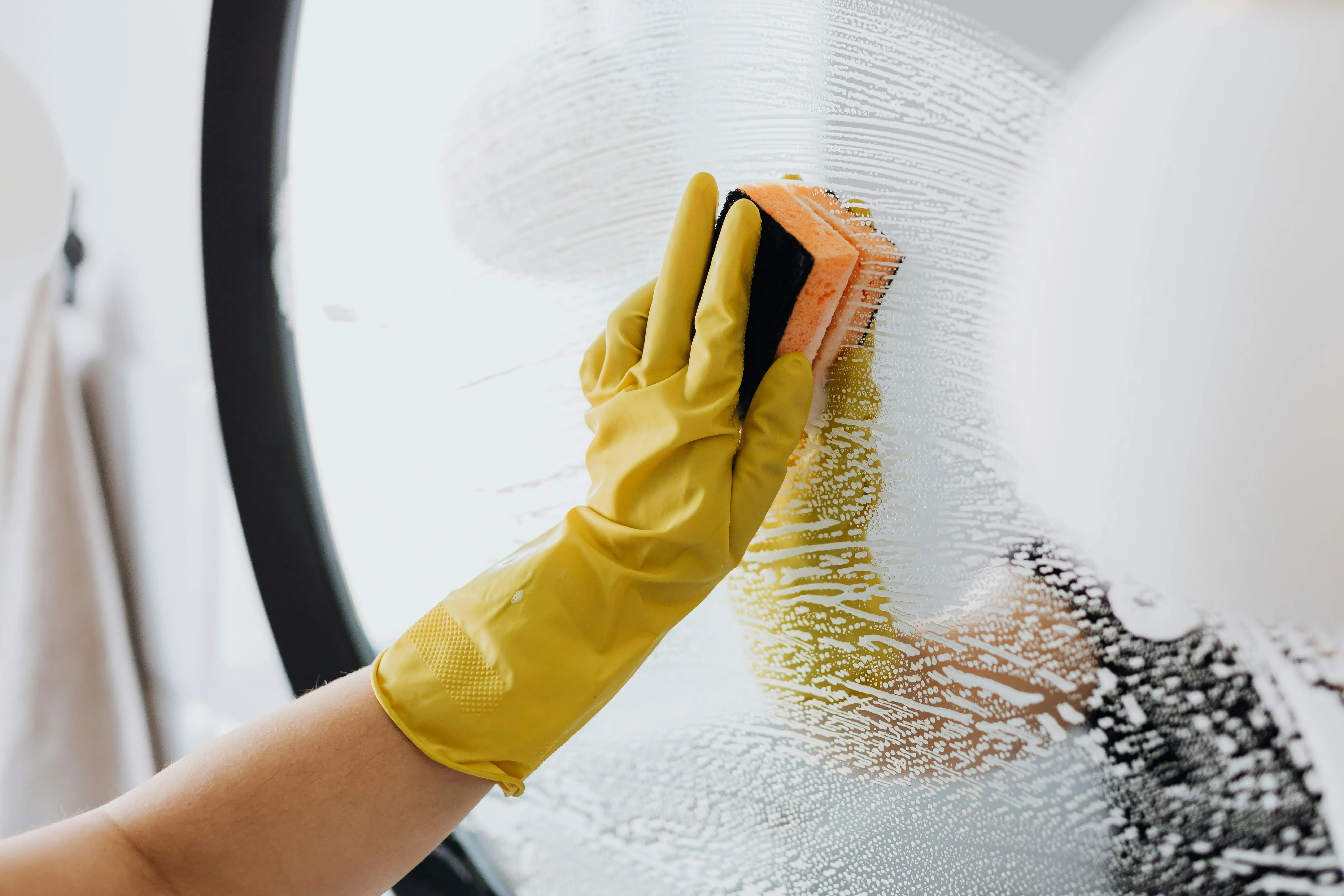 a full time maid in Abu Dhabi is cleaning the mirror of the house wearing the gloves in her hand