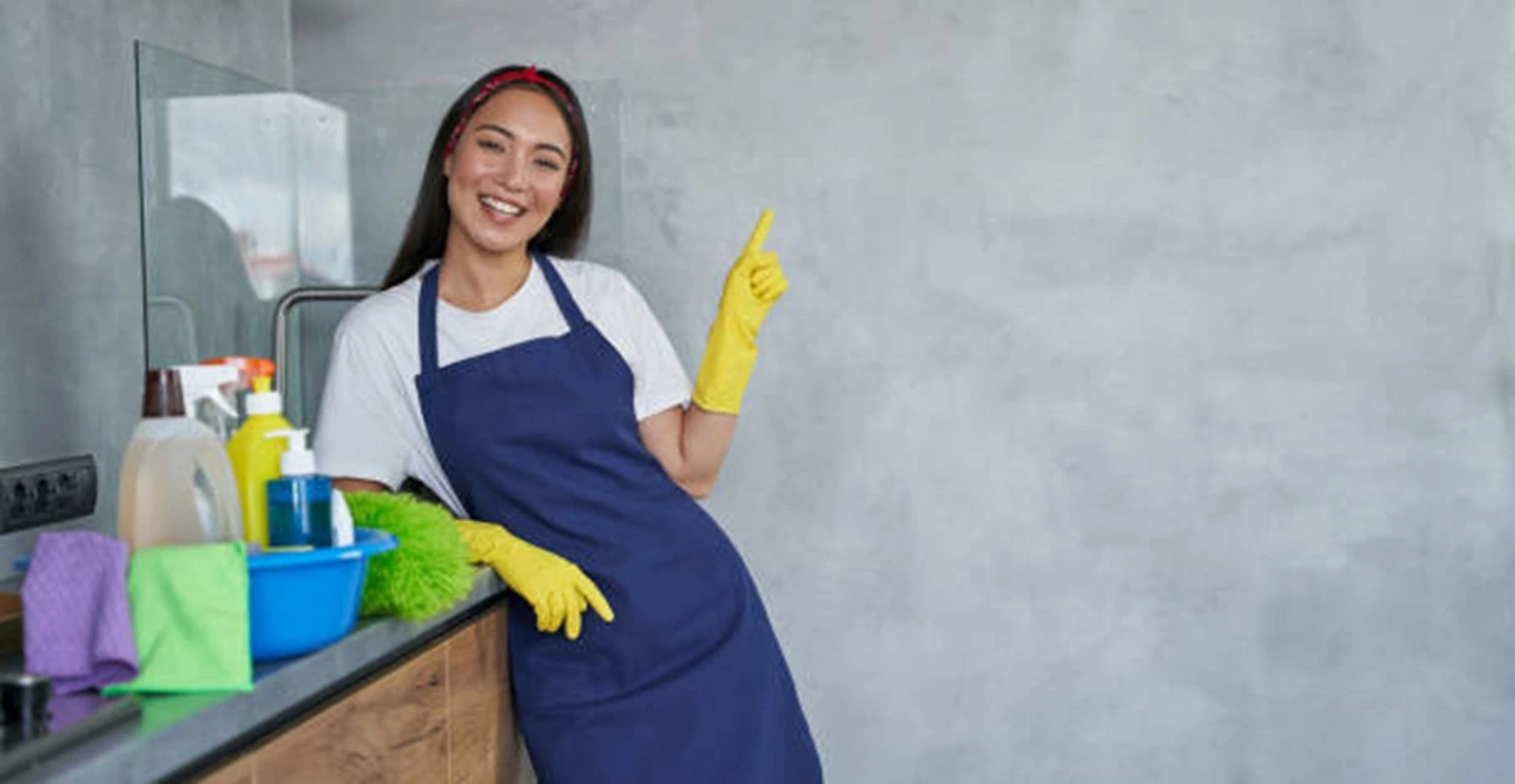 a filipino maid is point her hand up and similing while doing her work